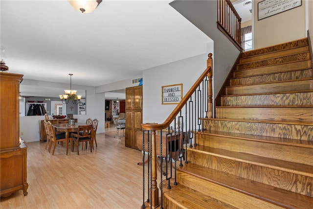 stairway featuring a notable chandelier and wood-type flooring