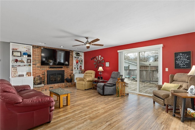 living room with a fireplace, ceiling fan, and light hardwood / wood-style flooring