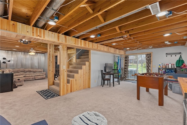 recreation room featuring carpet, ceiling fan, and wooden walls