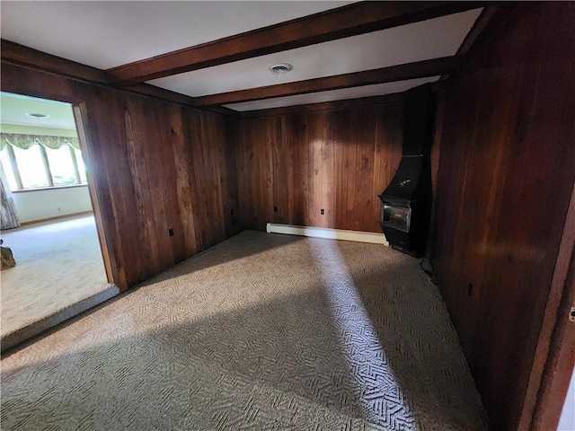 2638 E 1050th Ave, Oblong, IL 62449 - unfurnished room featuring a wood stove, beamed ceiling, wooden walls, and light carpet