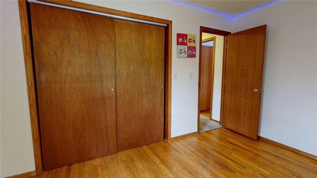 unfurnished bedroom with baseboards, a closet, and light wood-style flooring