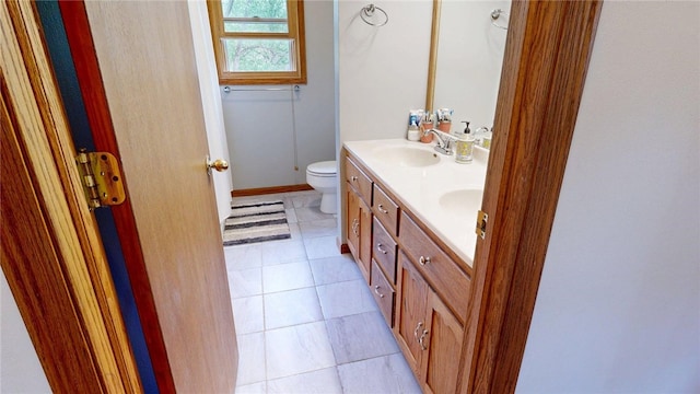 bathroom with a sink, tile patterned flooring, toilet, and double vanity