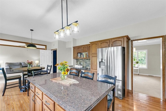 715 W Coolidge Ave, Charleston, IL 61920 - kitchen featuring stainless steel fridge, light wood-type flooring, pendant lighting, a kitchen island, and a breakfast bar