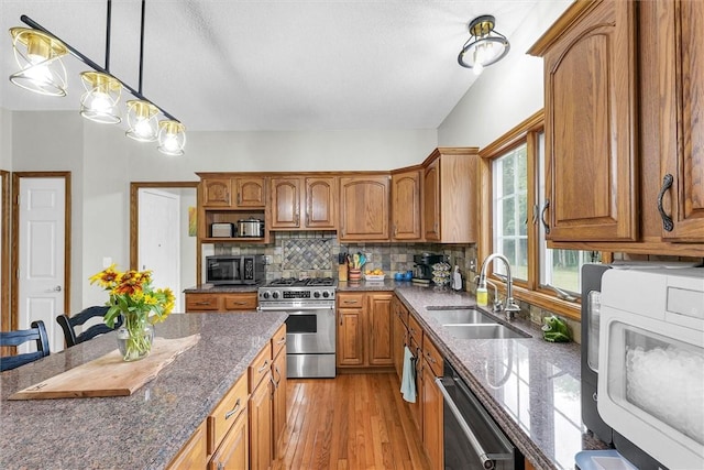 715 W Coolidge Ave, Charleston, IL 61920 - kitchen with stainless steel appliances, brown cabinets, decorative backsplash, light wood-type flooring, and hanging light fixtures