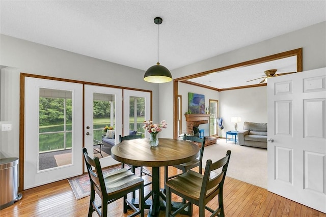 715 W Coolidge Ave, Charleston, IL 61920 - dining area with light wood-type flooring, french doors, a brick fireplace, a textured ceiling, and a ceiling fan