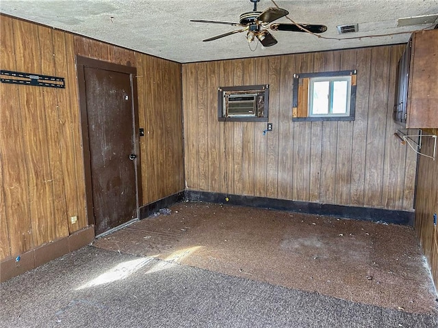 empty room with a textured ceiling, visible vents, baseboards, a ceiling fan, and a wall mounted AC