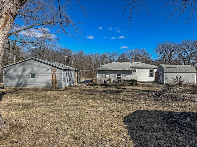 back of property featuring a shed, a deck, and an outdoor structure