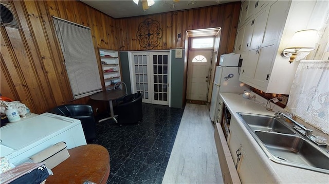 kitchen featuring white cabinets, french doors, sink, and wood walls