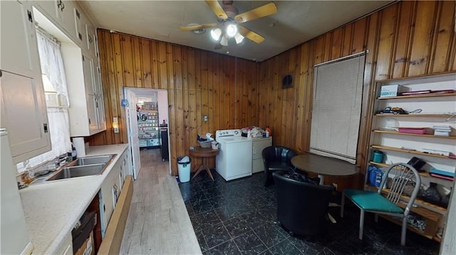 clothes washing area featuring ceiling fan, sink, dark hardwood / wood-style flooring, wood walls, and washer and clothes dryer