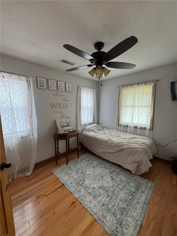 6414 300th Rd, Martinsville, IL 62442 - bedroom with multiple windows, a textured ceiling, light wood finished floors, and a ceiling fan