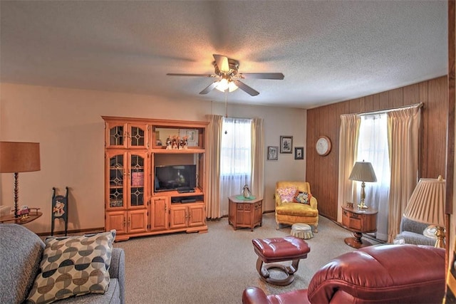 living room featuring ceiling fan, carpet flooring, a textured ceiling, and wood walls