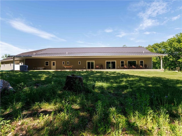 rear view of house with a lawn, metal roof, a standing seam roof, and central AC unit