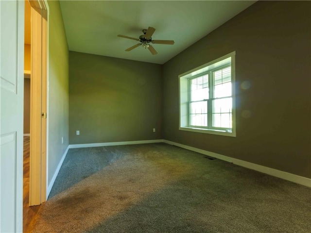 carpeted spare room featuring ceiling fan and baseboards