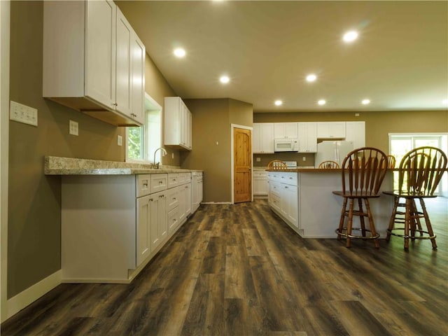 kitchen with white appliances, dark wood-type flooring, recessed lighting, white cabinets, and baseboards