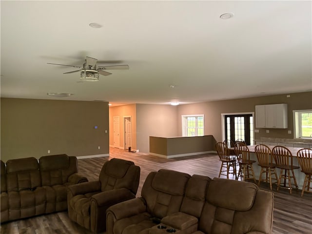 living room featuring dark wood finished floors, baseboards, and a ceiling fan