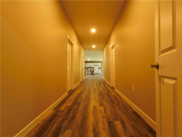 corridor with dark wood-type flooring, recessed lighting, and baseboards