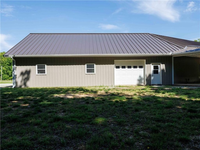 view of side of home with metal roof, a garage, and a lawn
