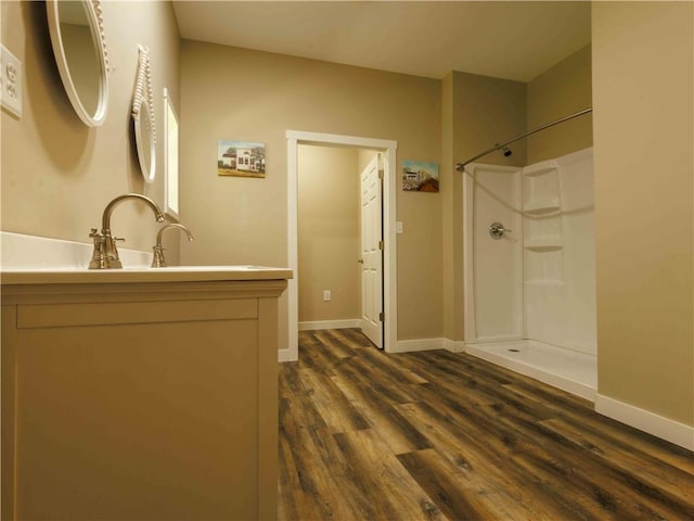 full bath with a shower, wood finished floors, vanity, and baseboards
