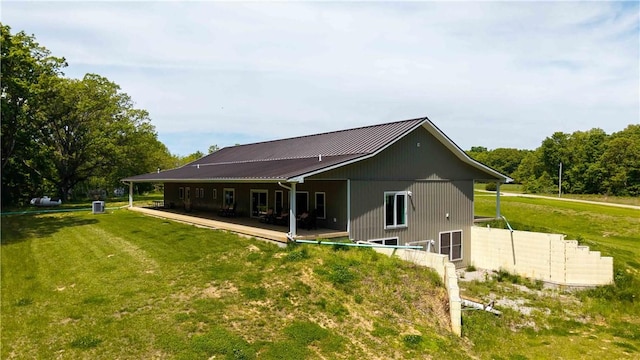 rear view of property with a lawn and metal roof