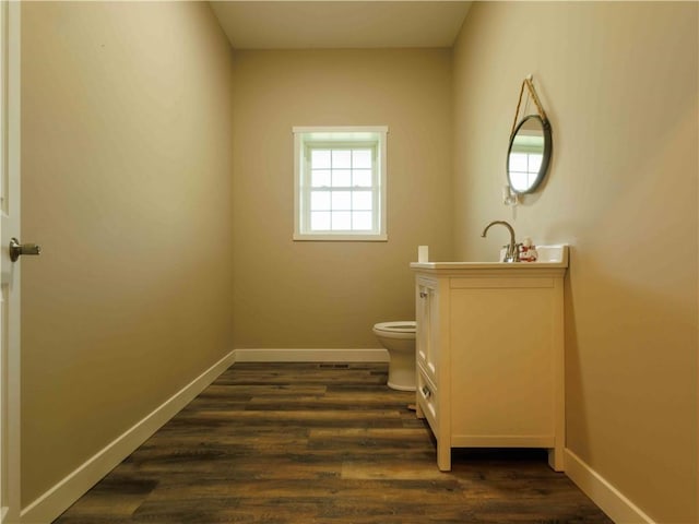 half bath featuring baseboards, vanity, toilet, and wood finished floors