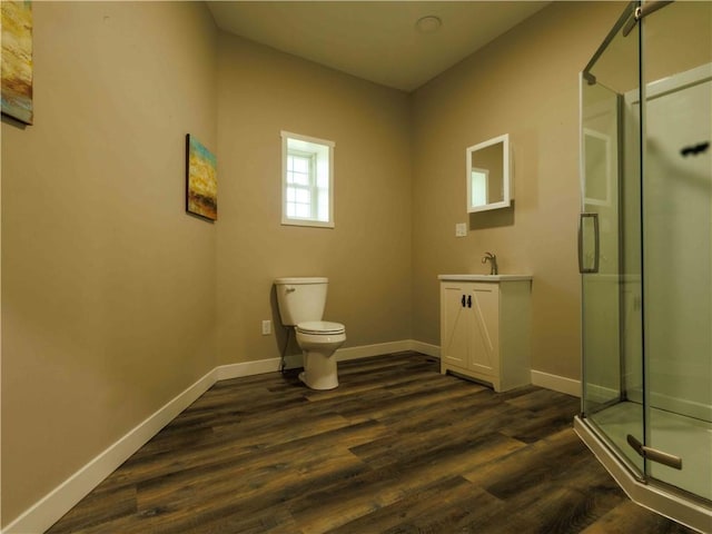 bathroom featuring a stall shower, baseboards, wood finished floors, toilet, and vanity