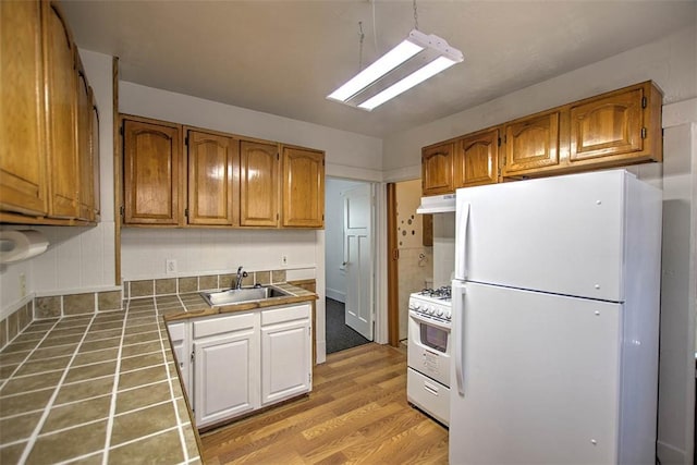1263 E Dickinson Ave, Decatur, IL 62521 - kitchen with white appliances, tile countertops, under cabinet range hood, light wood-style floors, and brown cabinetry