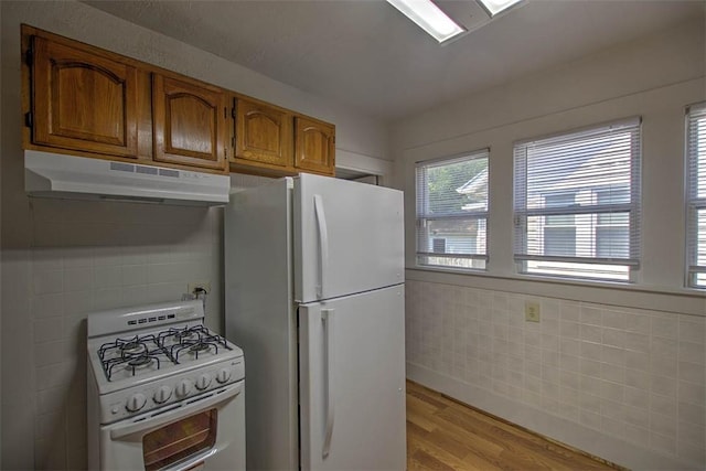 1263 E Dickinson Ave, Decatur, IL 62521 - kitchen with white appliances, under cabinet range hood, light wood-style flooring, tile walls, and brown cabinets