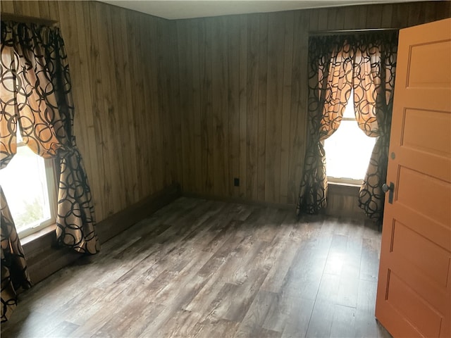 unfurnished room featuring wooden walls and hardwood / wood-style flooring