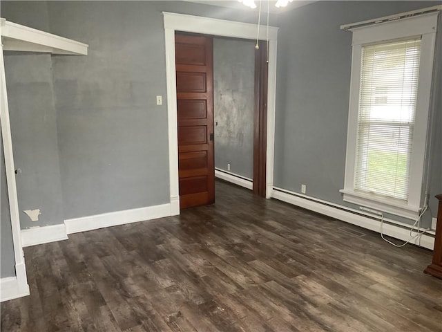 unfurnished room with dark hardwood / wood-style flooring, a baseboard radiator, and a wealth of natural light