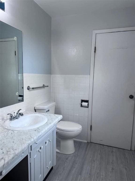 bathroom with vanity, wood-type flooring, tile walls, and toilet