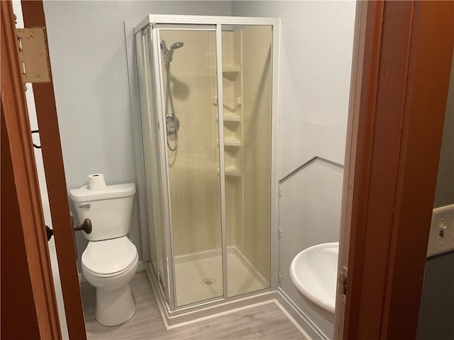 bathroom featuring hardwood / wood-style floors, an enclosed shower, and toilet