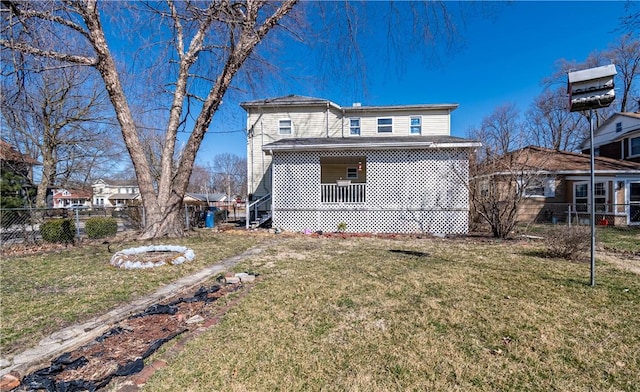 back of property with covered porch, a lawn, and fence