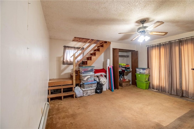 interior space featuring carpet, baseboard heating, a ceiling fan, and a textured ceiling