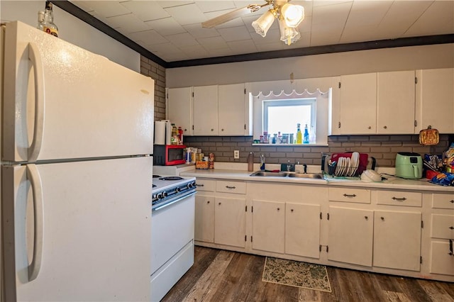 kitchen featuring backsplash, dark wood finished floors, light countertops, white appliances, and a sink