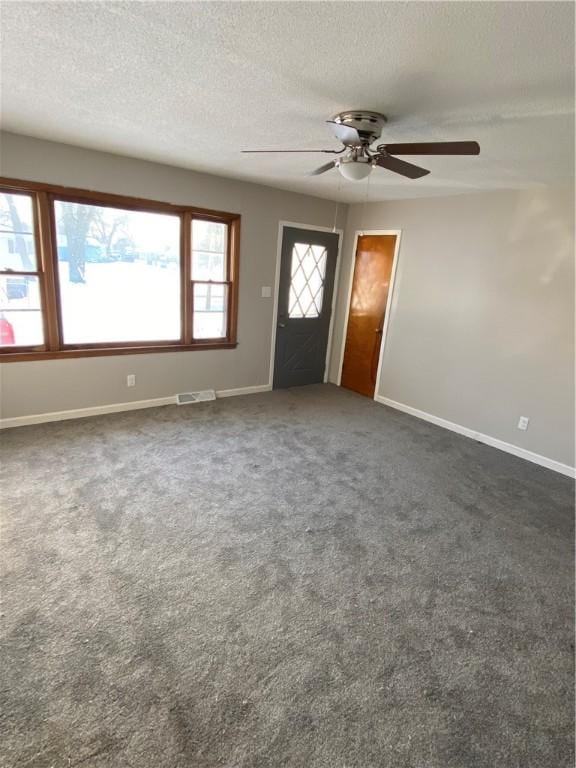 entryway with dark colored carpet, a wealth of natural light, a textured ceiling, and ceiling fan