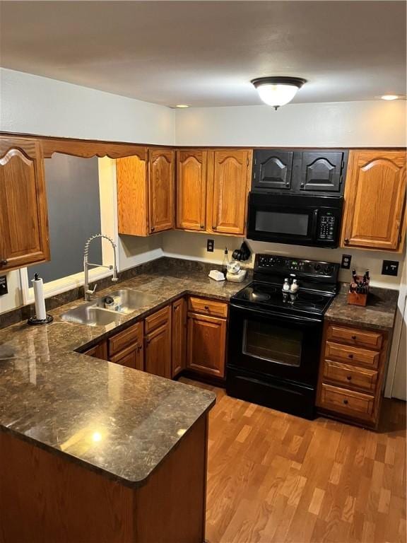 1021 W Hayes Ave, Charleston, IL 61920 - kitchen with black appliances, brown cabinetry, a peninsula, and light wood-type flooring