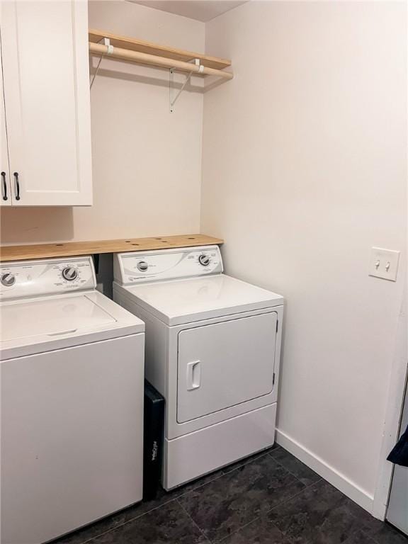 laundry area featuring washing machine and dryer, cabinet space, and baseboards