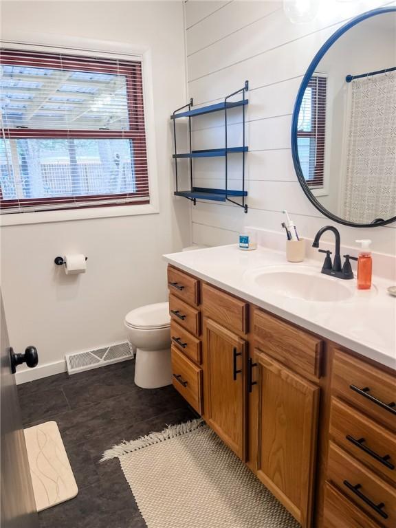 full bath with toilet, vanity, and visible vents