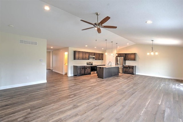 kitchen featuring ceiling fan with notable chandelier, an island with sink, pendant lighting, and stainless steel appliances