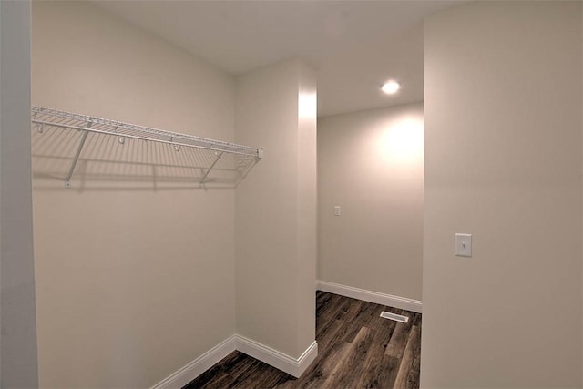 walk in closet with dark hardwood / wood-style floors