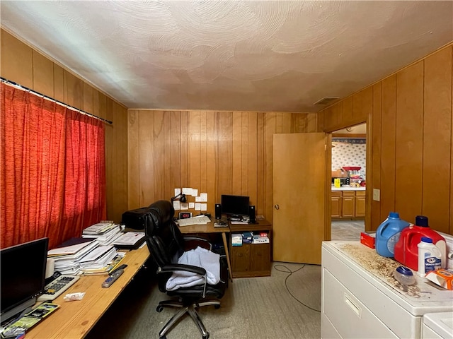 carpeted home office featuring separate washer and dryer and wood walls