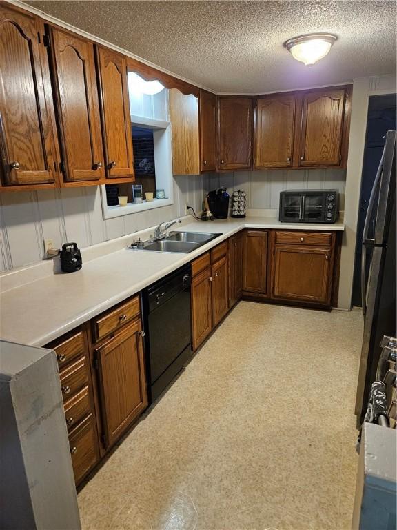 kitchen featuring sink, black appliances, and a textured ceiling