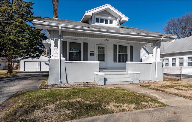 bungalow-style home featuring a detached garage, covered porch, and an outdoor structure