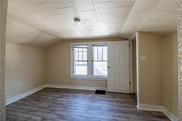 additional living space with visible vents, baseboards, lofted ceiling, and wood finished floors