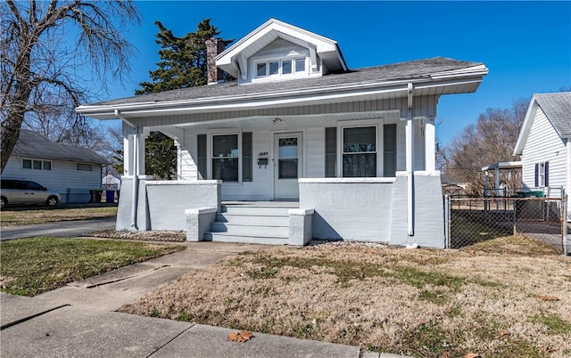 bungalow-style home with a porch, a chimney, and fence