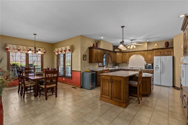 11284 E Lincolnshire Ln, Effingham, IL 62401 - kitchen with white appliances, a kitchen island, ceiling fan, a sink, and pendant lighting