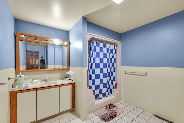 full bath featuring a wainscoted wall, visible vents, shower / bathtub combination with curtain, vanity, and tile patterned floors