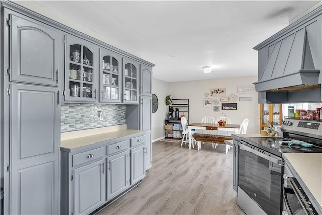 kitchen featuring gray cabinetry, custom exhaust hood, light wood-style flooring, and stainless steel range with electric cooktop