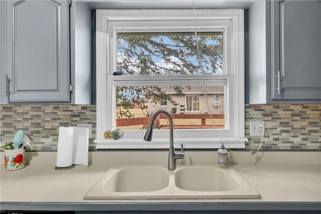 kitchen featuring light countertops, a healthy amount of sunlight, a sink, and gray cabinetry