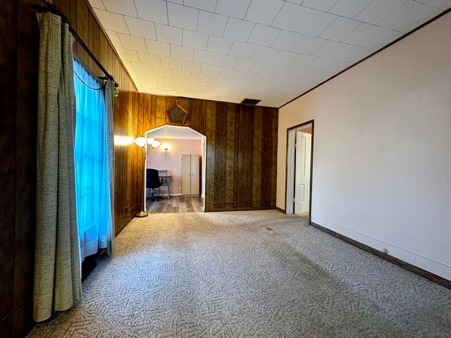 unfurnished room featuring wooden walls and carpet